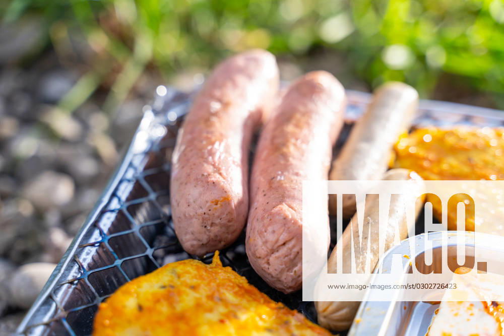 Bavaria, Germany - 2 September 2023: Vegetarian Grilling, Bratwurst Vegan and Vegetarian on a disposable grill on pebbles next to a meadow. Meat and sausage substitutes
