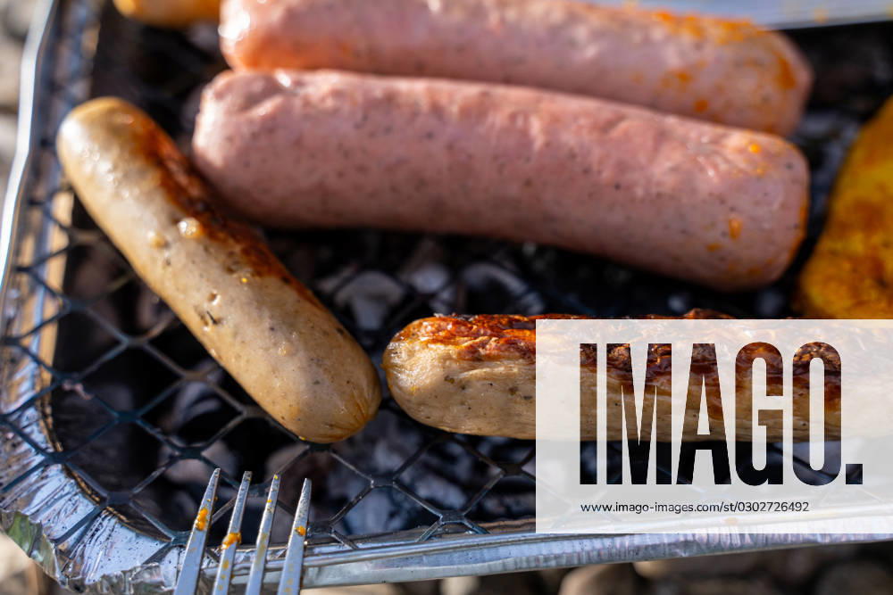 Bavaria, Germany - 2 September 2023: Vegetarian Grilling, Bratwurst Vegan and Vegetarian on a disposable grill on pebbles next to a meadow. Meat and sausage substitutes