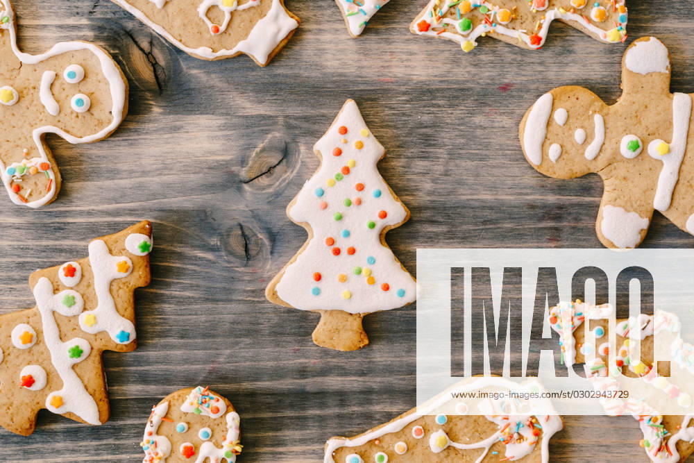 Close-up of Christmas gingerbread cookies on a wood texture. Fir-trees, little men and bells decorated with white glaze with multi-colored dots. Close-up of Christmas gingerbread cookies on a wood texture. Fir-trees, little men and bells decorated with white glaze with multi-colored dots. High quality photo