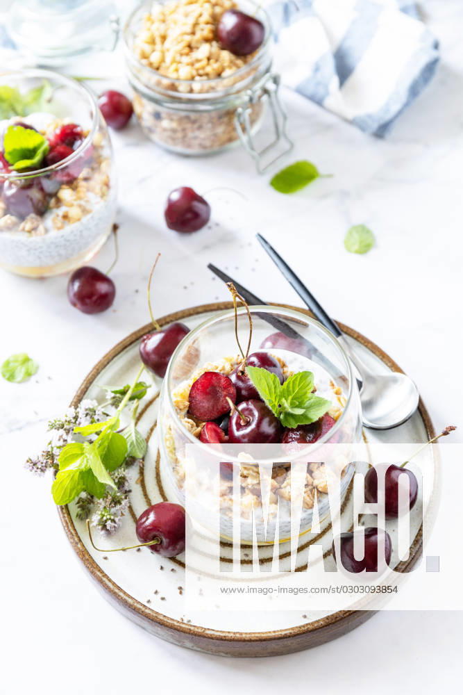 Healthy menu concept. Home made granola breakfast. Glass of parfait made of granola, berries cherry, yogurt with chia seeds on rustic table. Copy space. Healthy menu concept. Home made granola breakfast. Glass of parfait made of granola, berries cherry, yogurt with chia seeds on rustic table. Copy space.