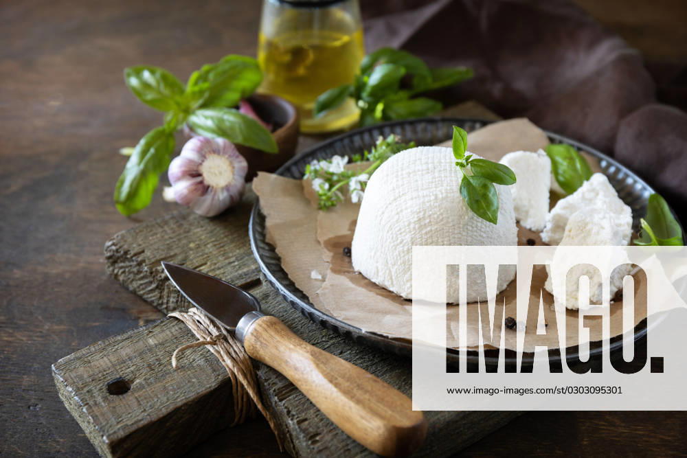 Homemade Italian ricotta cheese or cottage cheese with basil on a rustic table. Vegetarian healthy diet, fermentation food concept. Copy space. Homemade Italian ricotta cheese or cottage cheese with basil on a rustic table. Vegetarian healthy diet, fermentation food concept. Copy space.
