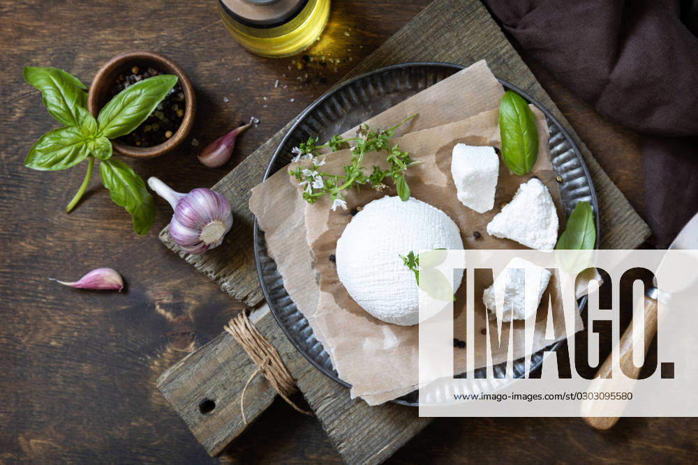 Homemade Italian ricotta cheese or cottage cheese with basil on a rustic table. Vegetarian healthy diet, fermentation food concept. View from above. Homemade Italian ricotta cheese or cottage cheese with basil on a rustic table. Vegetarian healthy diet, fermentation food concept. View from above.