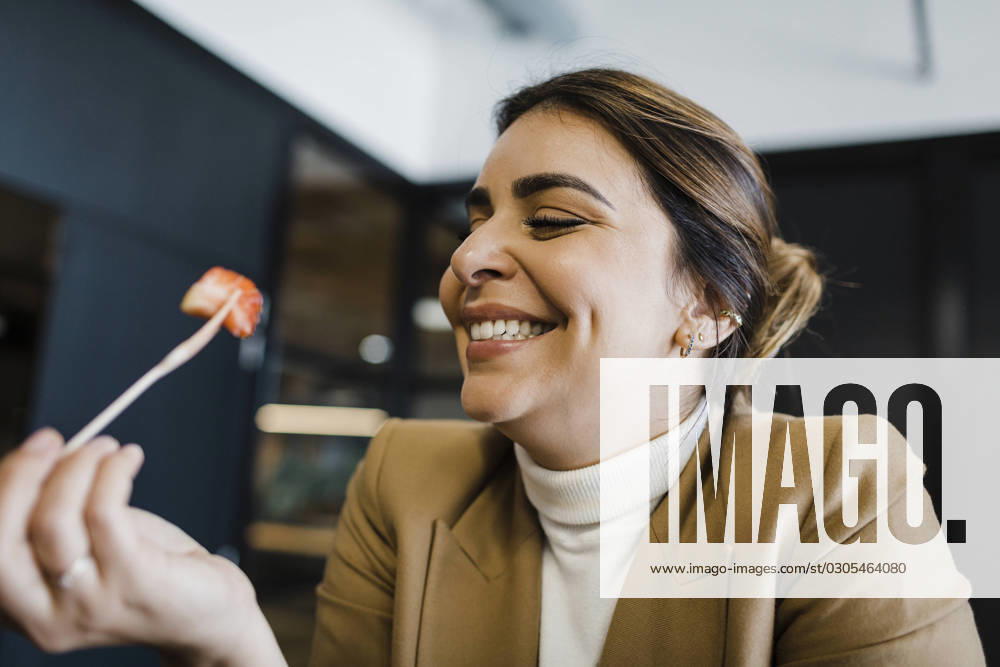 Happy businesswoman eating strawberry with fork at office model released, Symbolfoto property released, DCRF01782