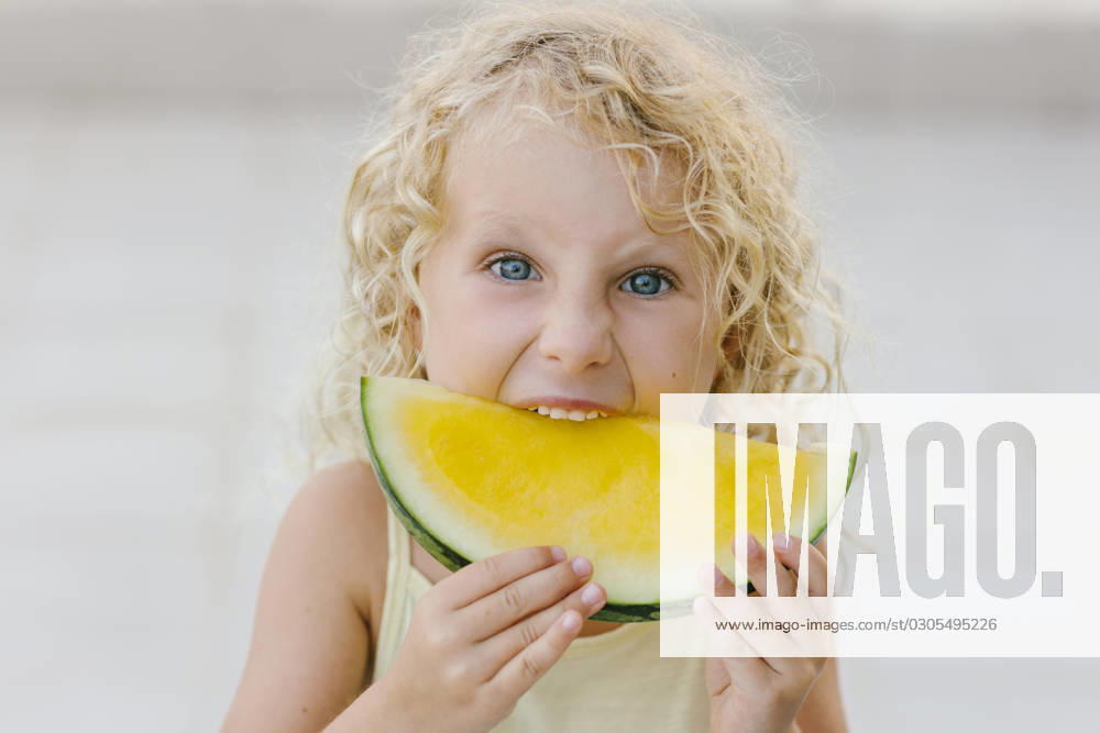 Blond girl biting slice of yellow watermelon model released, Symbolfoto, SIF00807