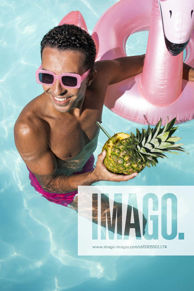 Happy man holding pineapple and swimming in water model released, Symbolfoto, VRAF00193