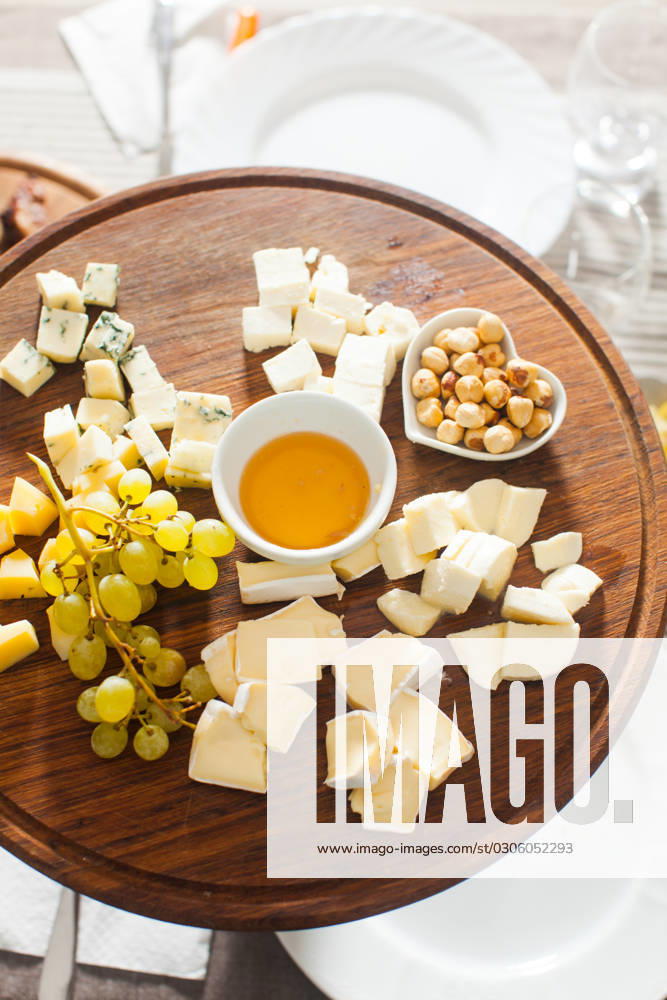 Cheese plate with hazelnuts, honey, grapes on wooden table Cheese plate with hazelnuts, honey, grapes on wooden table on the served table