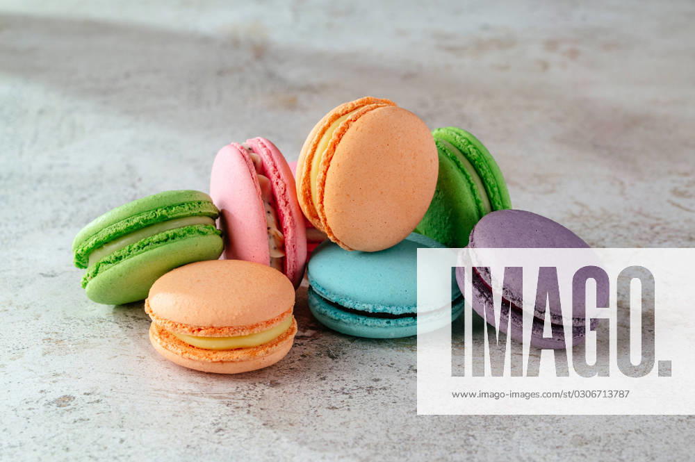 Multicolored macaroon cookies lie on a white kitchen table R_KUAL2310017C-1254979-01