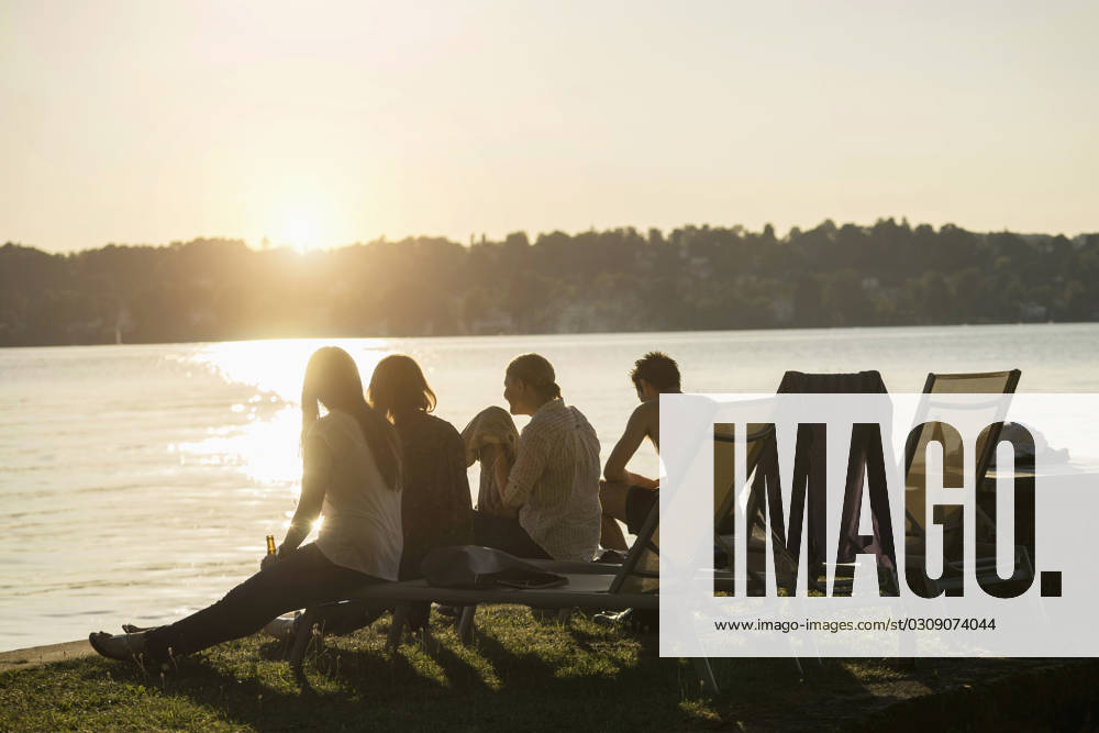 Group of young friends partying at lakeside during sunset, Bavaria, Germany Bavaria, Germany, Europe CR_RONI150802-00205-01 ,model released, Symbolfoto