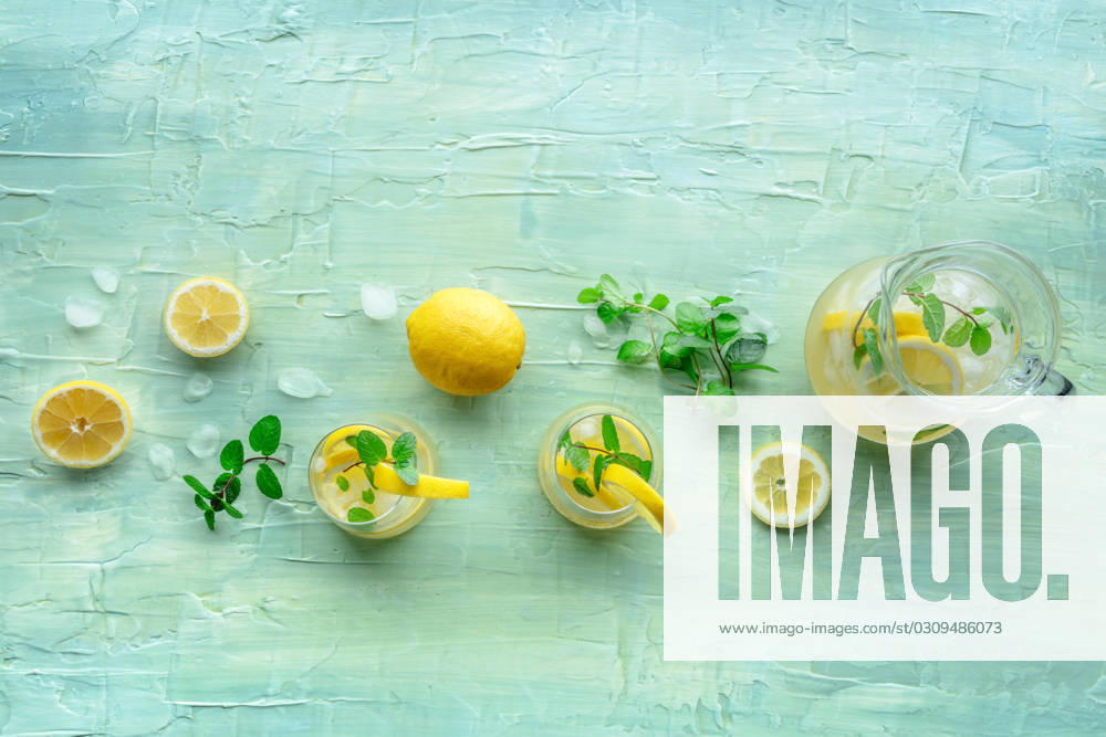 Lemonade with mint. Lemon water drink with ice. Two glasses and a pitcher Lemonade with mint. Lemon water drink with ice. Two glasses and a pitcher on a blue background, overhead flat lay shot. Detox beverage. Fresh homemade cocktail