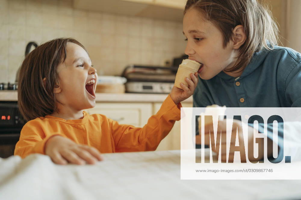 Happy boy feeding ice cream to brother at home model released, Symbolfoto property released, ANAF01484