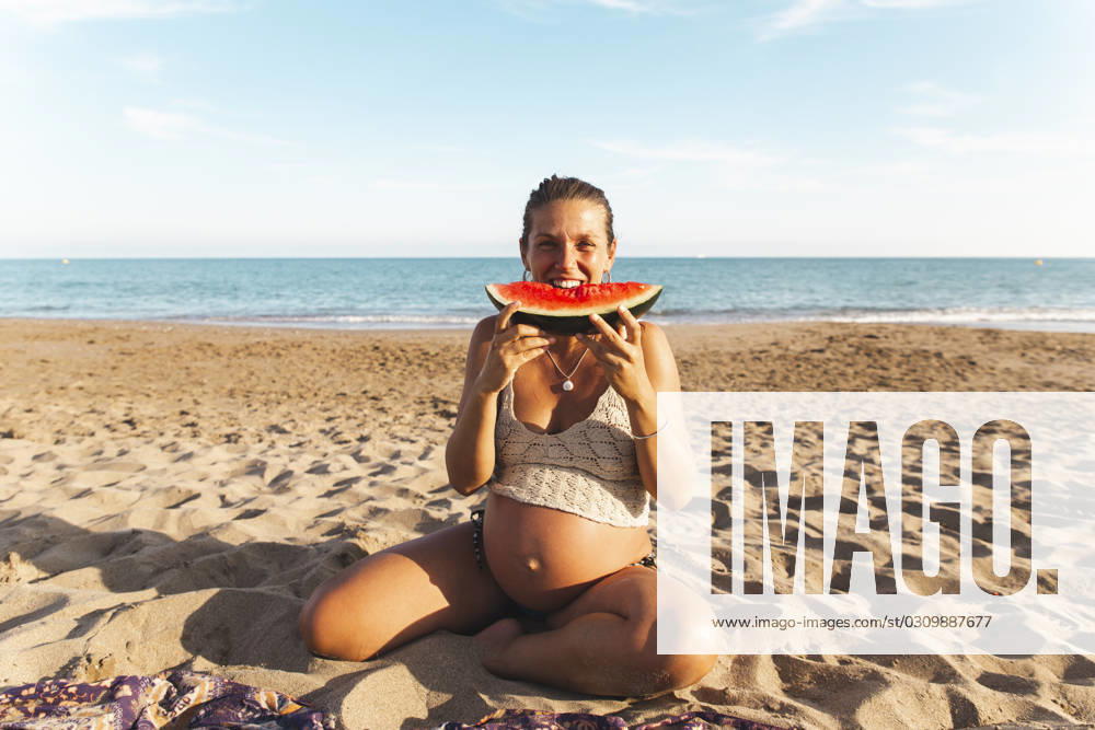 Pregnant woman sitting on sand and eating watermelon at beach model released, Symbolfoto, PCLF00714