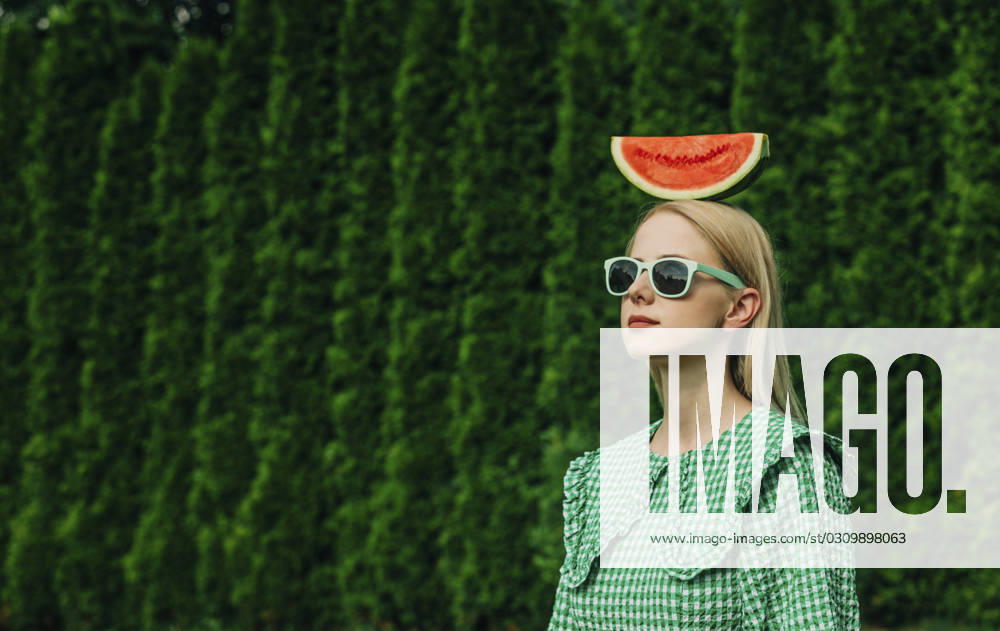 Woman wearing sunglasses standing with watermelon on head in garden model released, Symbolfoto, VSNF01092