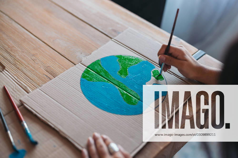 Close-up of a young woman s hands as she paints an earth design on cardboard, symbolizing environmental awareness and care. Model Released EricPanades_ID16562_503318_009