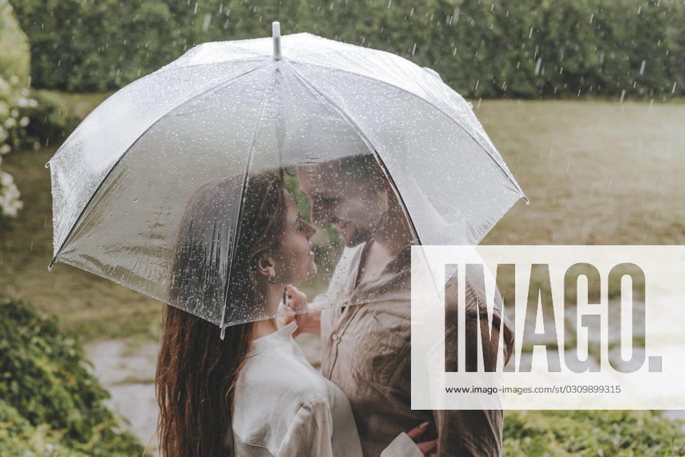 Romantic couple standing with umbrella in rain at garden model released, Symbolfoto, YTF00930