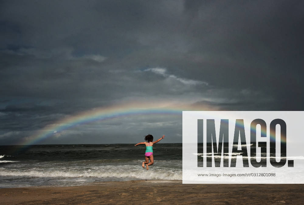 Young girl jumping in the ocean under rainbow Avon, North Carolina, United States CR_JOKU231105-1281095-01 ,model released, Symbolfoto