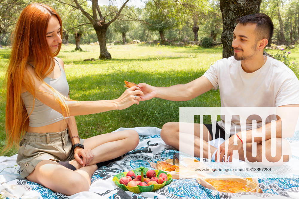 MR_ID17146_15419_JaimePineda.jpg, MR_ID17146_15418_NataliaPenado.jpg Young couple enjoying a picnic in a sunny park, sharing food and moments together under a tree in summer day Model Released GemaAlejo_ID17146_522142_001