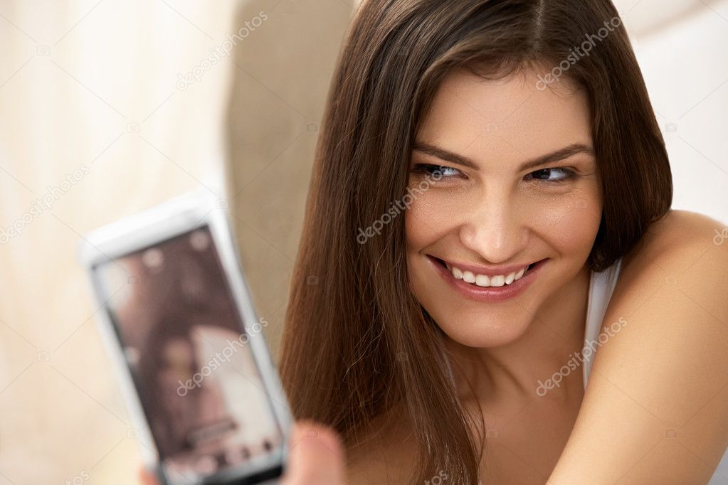 Portrait of a Young Woman Holding a Smartphone Digital Camera and Taking a Selfie model released
