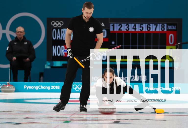 GANGNEUNG, SOUTH KOREA – FEBRUARY 13, 2018: Curler Alexander Krushelnitsky (L) looks on as Anastasia Bryzgalova, Olympic Athletes from Russia, delivers a stone in their mixed doubles curling bronze medal match against Norway s Kristin Skaslien and Magnus Nedregotten during the 2018 Winter Olympic Games Olympische Spiele Olympia OS at the Gangneung Curling Centre. Olympic Athletes from Russia won the game 8:4. Valery Sharifulin TASS TS0738B1