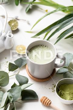 A vertical shot of Green tea latte with milk in a white cup with green leaves and wooden spoon tea, green, latte, drink, cup, beverage, food, hot, milk, white, coffee, background, cafe, sweet, table, cream, fresh, breakfast, refreshment, mug, healthy, matcha, japanese, green tea, glass, cappuccino, espresso, liquid, natural, chinese, foam, morning, wooden, wood, tasty, powder, brown, oriental, caffeine, cold, nutrition, relax, cool, iced, ice, organic, delicious, smoothie, nobody, isolated