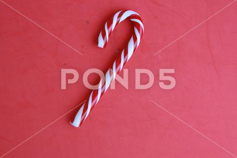 A top view of a candy cane under the lights against a pink background candy, red, cane, background, white, holiday, christmas, xmas, decoration, traditional, winter, striped, sweet, sugar, festive, peppermint, food, stripe, classic, merry, stick, year, new, dessert, seasonal, top, view, treat, unhealthy, flavor