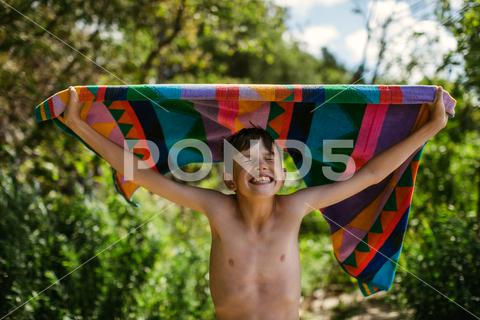 Young boy with towel at beach on summer vacation with a big smile bare, bathing, beach, bluesky, boys, colours, fun, happy, holidays, joy, lake, laughing, ocean, retreat, smile, summer, swim, teenager, teeth, towel, trees, vacation, wet