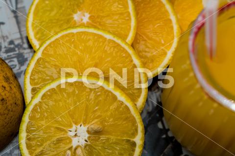 A closeup of sliced lemons near a glass of juice bright, citrus, closeup, color, cut, food, fresh, fruit, healthy, juice, lemons, refreshment, ripe, tasty, tropical, vegetarian, vitamin, yellow