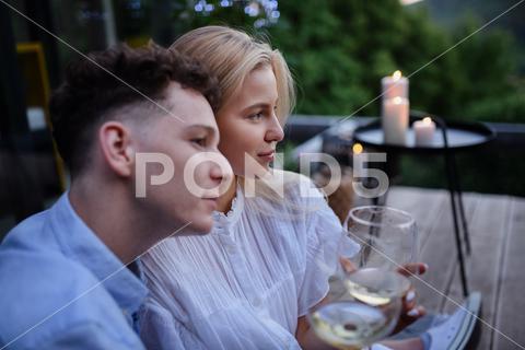 A young couple clinking with wine outdoors, weekend away in tiny house in countryside, sustainable living. love, wine, couple, woman, man, outdoor, happy, terrace, romance, romantic, together, young, drink, glass, person, smiling, caucasian, celebration, lifestyle, garden, party, relationship, two, alcohol, cheerful, vacation, tourism, closeness, date, honeymoon, newlyweds, lover, positive, togetherness, drinking, champagne, evening, holding, tiny house, holiday, nature, off beat, relax, meditation, digital detox, candle, hygge, travel, weekend away