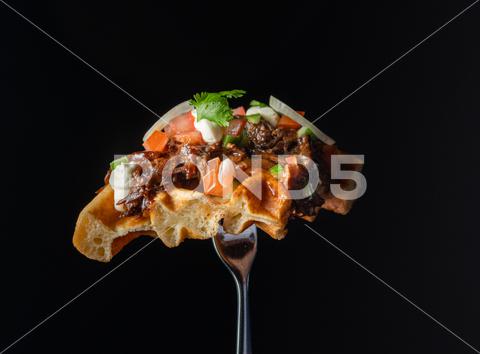 A closeup shot of a waffle on a fork with salmon and onions art, background, black, color, cuisine, dark, delicious, design, dessert, food, fork, glass, gourmet, isolated, meal, onions, restaurant, salmon, tasty, waffle, white