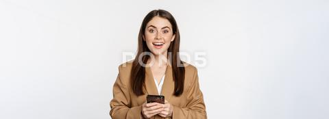 Smiling businesswoman using smartphone, app on mobile phone, standing over white background. woman, office, mobile phone, cellphone, cellular, app, smartphone, online, store, business, network, digital nomad, professional, corporate, businesswoman, girl, background, person, face, technology, white, isolated, attractive, young, happy, beautiful, adult, pretty, one, portrait, confident, manager, people, executive, smile, lady, looking, job, worker, career, cheerful, success, occupation, standing, successful, entrepreneur, beauty, consultant, lifestyle