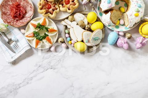 Festive dinner, Easter brunch. Easter table scene with an assortment of baking, desserts, stuffed eggs and dyed eggs on a marble background. View from above. Copy space. above, easter, egg, assortment, background, sweet, dessert, bunny, party, traditional, delicious, buffet, view, variety, top, table, springtime, spring, seasonal, overhead, holiday, food, celebration, colorful, candy, flat lay, snack, season, chocolate, homemade, cookies, tart, baking, braided, decoration, bread, animal, border, festive, sweets, desserts, pastry, appetizer, breakfast, cake, buns, copy space, setting, treats