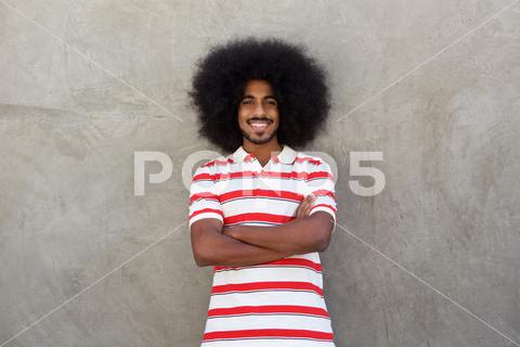 Portrait of smiling young man with afro and striped shirt adult, african, afro, american, arms crossed, attractive, background, beard, black, carefree, casual, cheerful, concrete, confidence, confident, copy space, enjoy, expression, face, fashion, fashionable, guy, hairstyle, handsome, happiness, happy, indian, life, lifestyle, looking, male, man, model, modern, one, people, person, portrait, posing, real, relax, shirt, smiling, standing, striped, style, wall, young