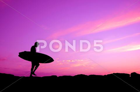 Vacation silhouette of a surfer carrying his board against a purple sunset activity, australia, beach, board, california, carry, carrying, coast, copy, dawn, dude, dusk, exercise, fun, hawaii, holiday, home, man, nature, ocean, pacific, paradise, people, person, pink, purple, recreation, rocks, sea, silhouette, sky, space, sport, surf, surfboard, surfer, surfing, travel, tropical, tropics, twilight, vacation, walk, water, waves