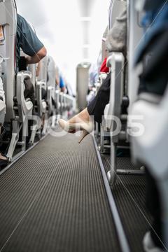 Interior of commercial airplane with passengers in their seats during flight. Corridor, aeroplane, air, aircraft, airline, airplane, aisle, attandant, business, cabin, carrier, chairs, commercial, crowded, economy, entertaiment, flight, indoor, inside, interior, jet, job, journey, light, man, modern, multimedia, passenger, people, plane, public, rear, row, screen, seat, seating, serve, service, sky, stewardess, tourism, tourist, transporation, transport, transportation, travel, trip, voyage, work