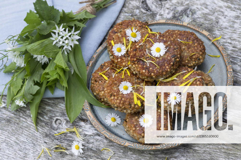 Homemade Herb patties with Baerlauch at a Plate, decorated with Goosebumps selfmade Herb PATTIES With Wild garlic ON a plate, decorated With daisies BLWS698282