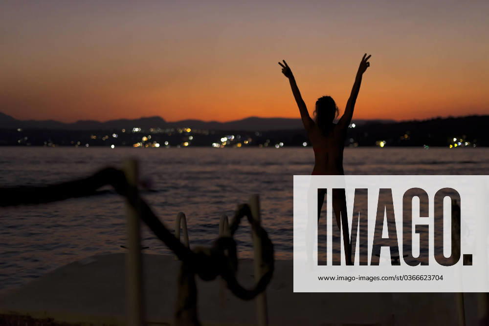 Silhouette of a young girl joyful with her arms up on a lake at dusk Tequesquitengo, Morelos, Mexico R_XAXA220301F7-940553-01 ,model released, Symbolfoto