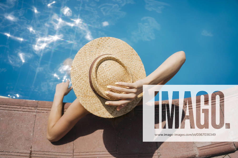 Woman wearing straw hat relaxing in pool on sunny day model released, Symbolfoto, YBF00280