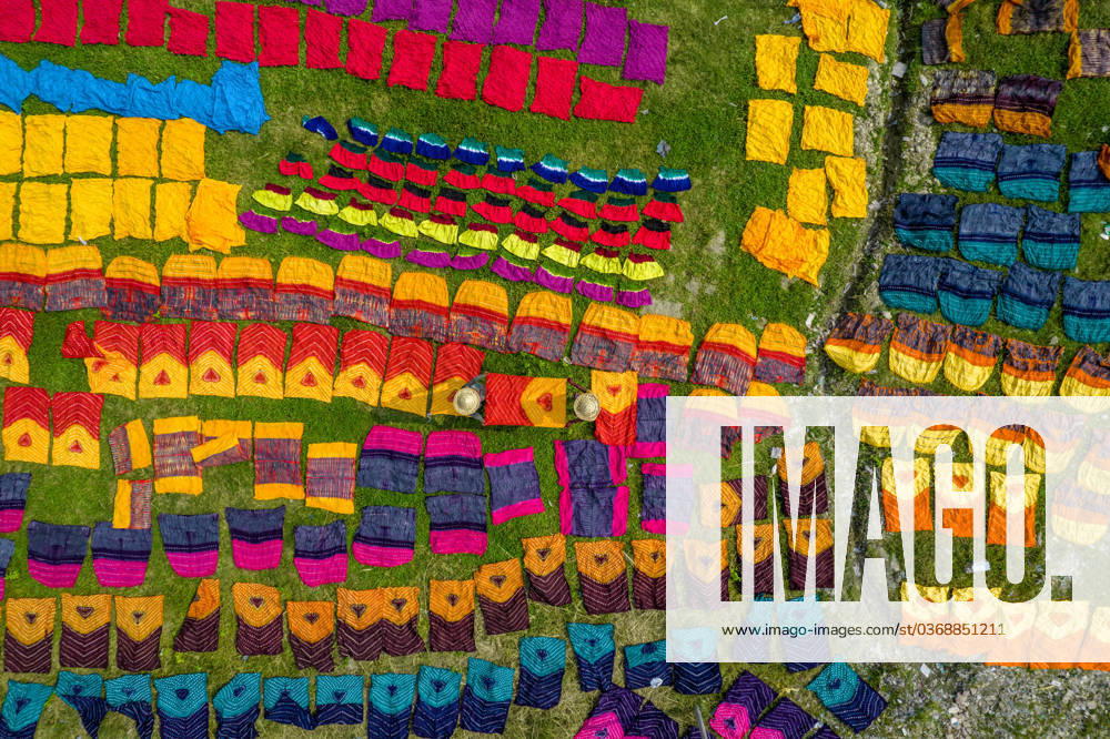 Workers spread colored cloths and sarees on a field to dry under the hot sun after the fabric is dyed at Batik Village at Narayanganj, Bangladesh. Once they are dry - which usually takes four hours - they are made into clothes which are sold worldwide. Narayanganj Bangladesh - ZUMAr337 20231030_zip_r337_002