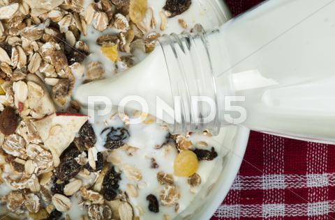 Muesli breakfast in package.Bottle milk and spoon. Pouring milk in a bowl close up closeup Muesl grain meal table nobody milk dessert banana diet snack horizontal breakfast wheat nuts light gourmet crunchy raspberry spoon oat flakes eat energy tasty dried corn almond nutrition fiber dietary food raw vegetarian bowl sweet cornflakes healthy