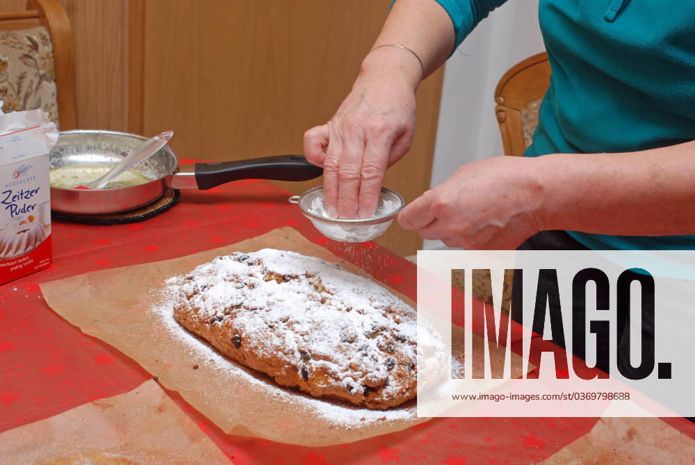 Baking stollen Germany Saxony Anhalt Altmark Altmarkkreis Salzwedel Kusey Stollen baking ready-baked quark stollen are placed on baking paper in the kitchen to cool before they are finally spread with melted butter and sprinkled with sugar and powdered sugar