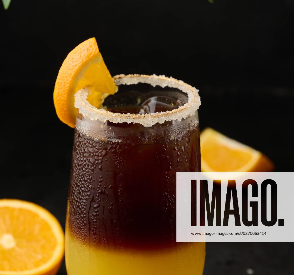 Iced coffee with orange juice in a transparent glass, refreshing bumble coffee on the table, black background Iced coffee with orange juice in a transparent glass, refreshing bumble coffee on the table, black background