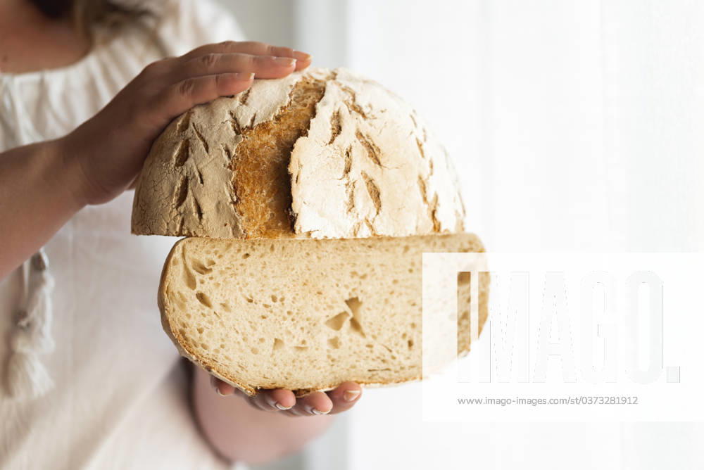 Sourdough bread hold in hands. No yeast bread Unrecognizable woman holding sourdough bread, homemade with wheat flour and starter. No yeast bread. Natural leaven loaf. Rustic round bread.