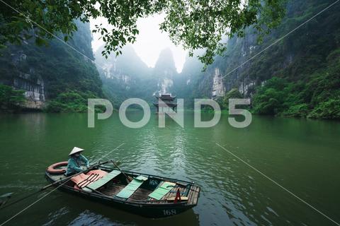 Boat rowing along the Thung Chuoi temple gate between lush green karst mountains, Trang An, Ninh Binh, Vietnam ninh binh trang an vietnam boat water river temple gate karst mountain thung chuoi journey mist panorama green hat rowing indochina limestone nature asia asian landscape land paddling rural scenic country destination touristic beautiful countryside travel exotic fog formation high peak rock adventure blue cloud grass hill holiday outdoors tourism tour lush