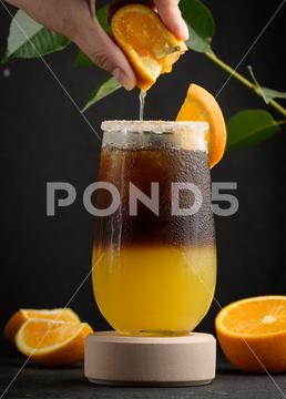 Iced coffee with orange juice in a transparent glass, a woman's hand squeezes an orange slice into a bubble drink coffee ice juice juicy layer morning nobody orange slice squeeze sweet syrup table yellow cold cool drink drop espresso fresh fruit glass hand beverage black brown bumble caffeine citrus cocktail