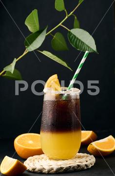 Iced coffee with orange juice in a transparent glass, refreshing bumble coffee on the table, black background layer coffee orange brown sweet cool ice espresso cold drink glass fresh juice beverage cocktail morning caffeine fruit syrup table yellow citrus juicy bumble slice nobody black
