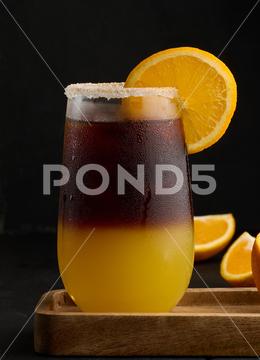 Iced coffee with orange juice in a transparent glass, refreshing bumble coffee on the table, black background layer coffee orange brown sweet cool ice espresso cold drink glass fresh juice beverage cocktail morning caffeine fruit syrup table yellow citrus juicy bumble slice nobody black