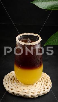 Iced coffee with orange juice in a transparent glass, refreshing bumble coffee on the table, black background layer coffee orange brown sweet cool ice espresso cold drink glass fresh juice beverage cocktail morning caffeine fruit syrup table yellow citrus juicy bumble slice nobody black