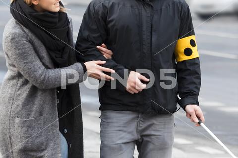 Young Woman Assisting Blind Man With White Stick On Street blind help cross street disable man person day road adult woman assist car walking vision cane sign black disability helping assistant people stick guiding white safety crossing transport