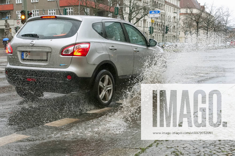 Berlin, GER car driving on a road through a big puddle everyday life, aquaplaning, exterior, exterior shot, automobile, car, car traffic
