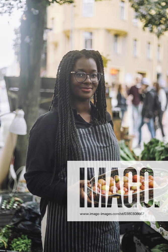 IMAGO Creative, Jahreszeit Sommer, Food, Pflaume Portrait of smiling female vendor holding tray of fresh plums while standing at farmer s market Sweden, Stockholm, model released