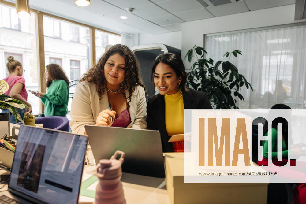 Smiling female entrepreneurs discussing over laptop while working at office Sweden, Stockholm, model released, property released